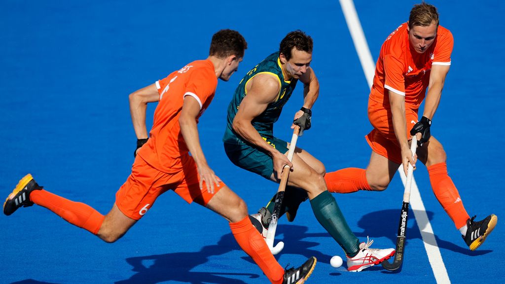 Thomas Craig, en el centro de azul, rodeado por dos jugadores de la seleción de hockey de los Países Bajos