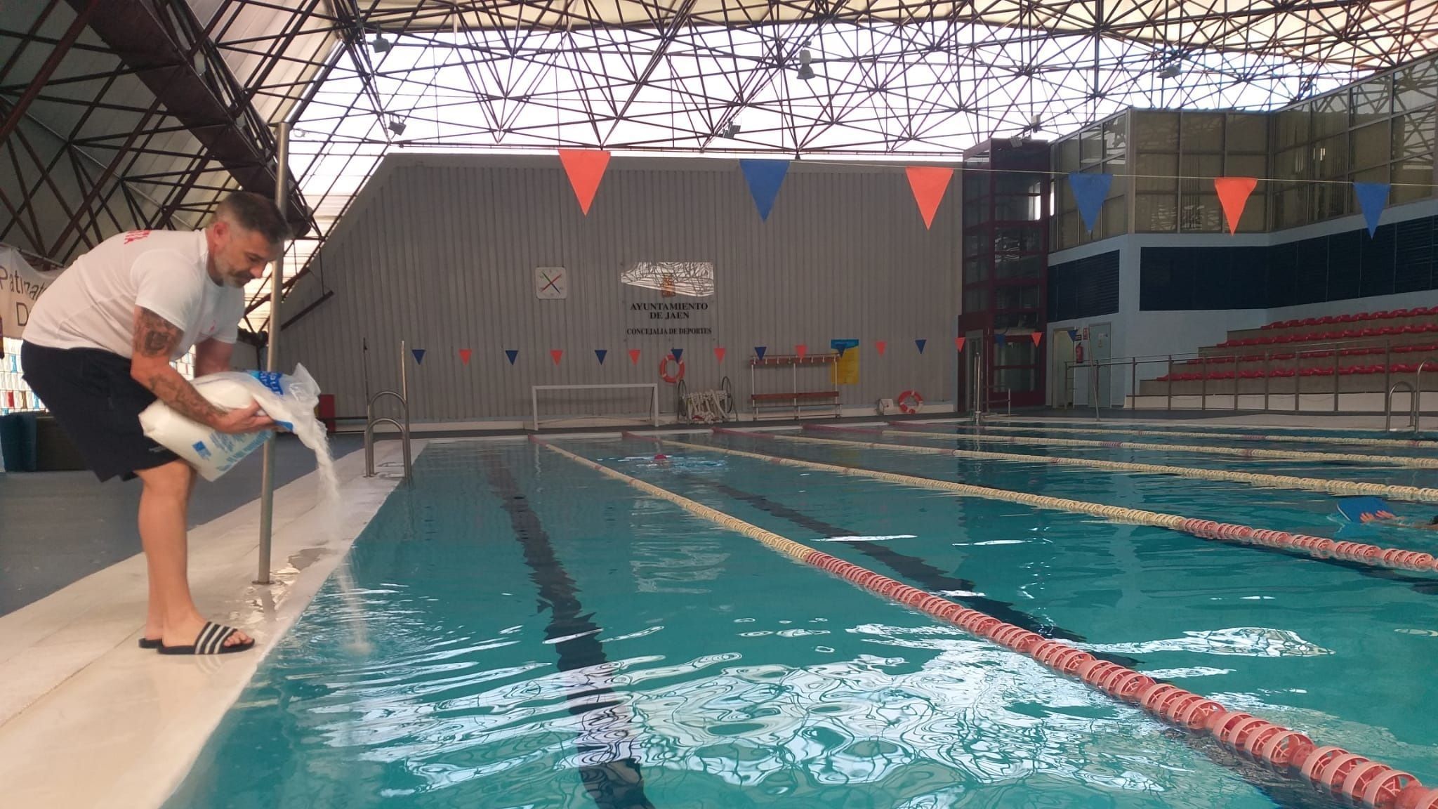 Un trabajador echa cloro en una piscina