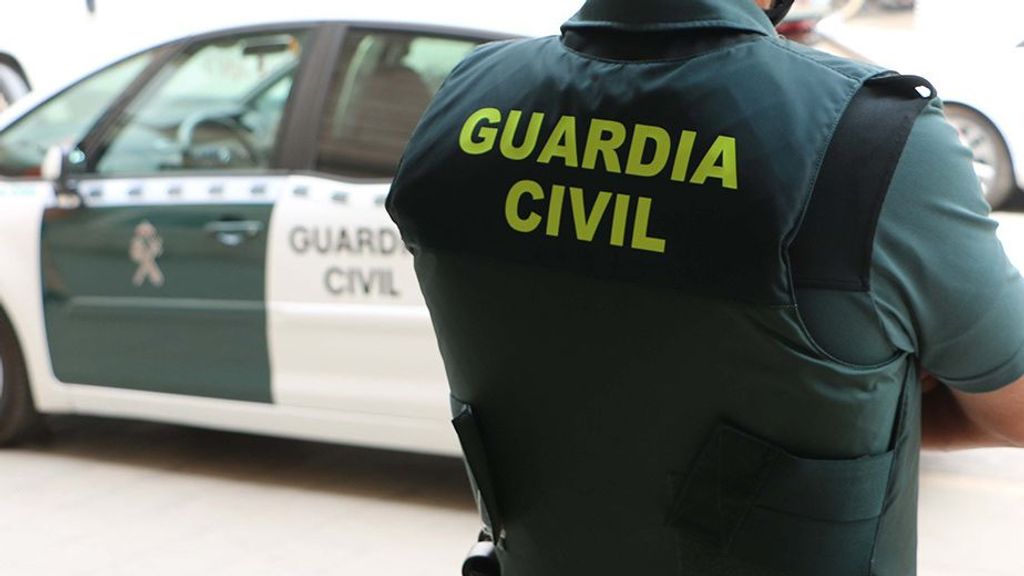 Un agente de la Guardia Civil, de espaldas, junto a un vehículo oficial.