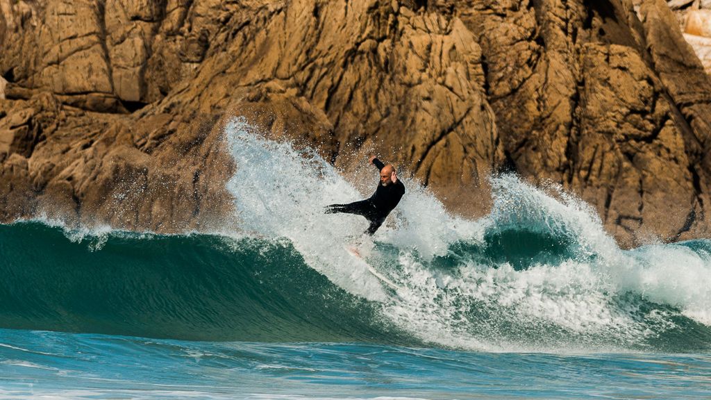 Derick Rey surfea una ola con su tabla