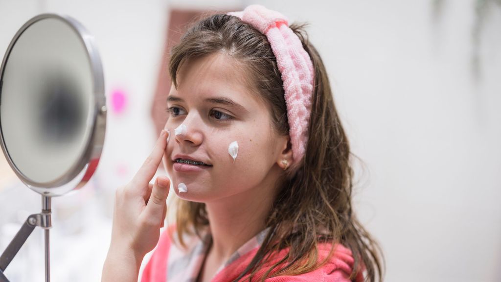 Una niña echándose crema en la cara