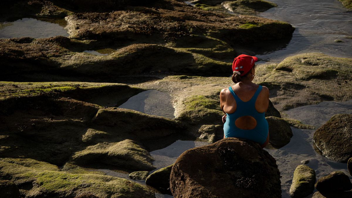 Una bañista disfruta en las rocas de una playa en la provincia de Pontevedra