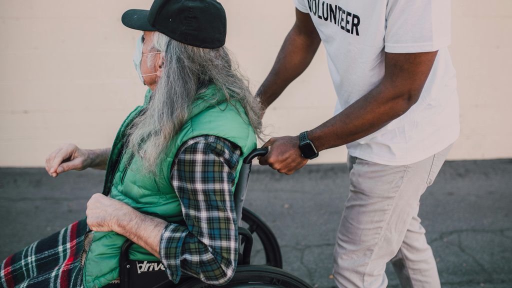 Un chico paseando a una mujer mayor