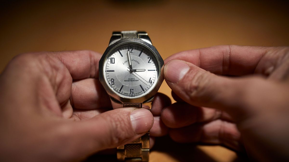 Un hombre cambia las manecillas de un reloj