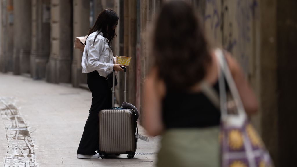 Una mujer, ajena a esta información, con su maleta accediendo a un hotel.