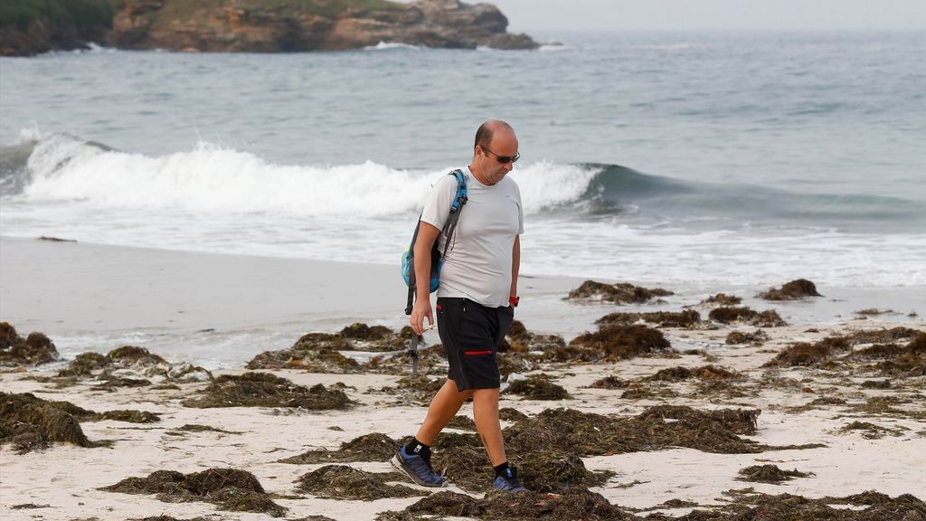 Un hombre pasea durante la pleamar en la playa de A Rapadoira, Lugo