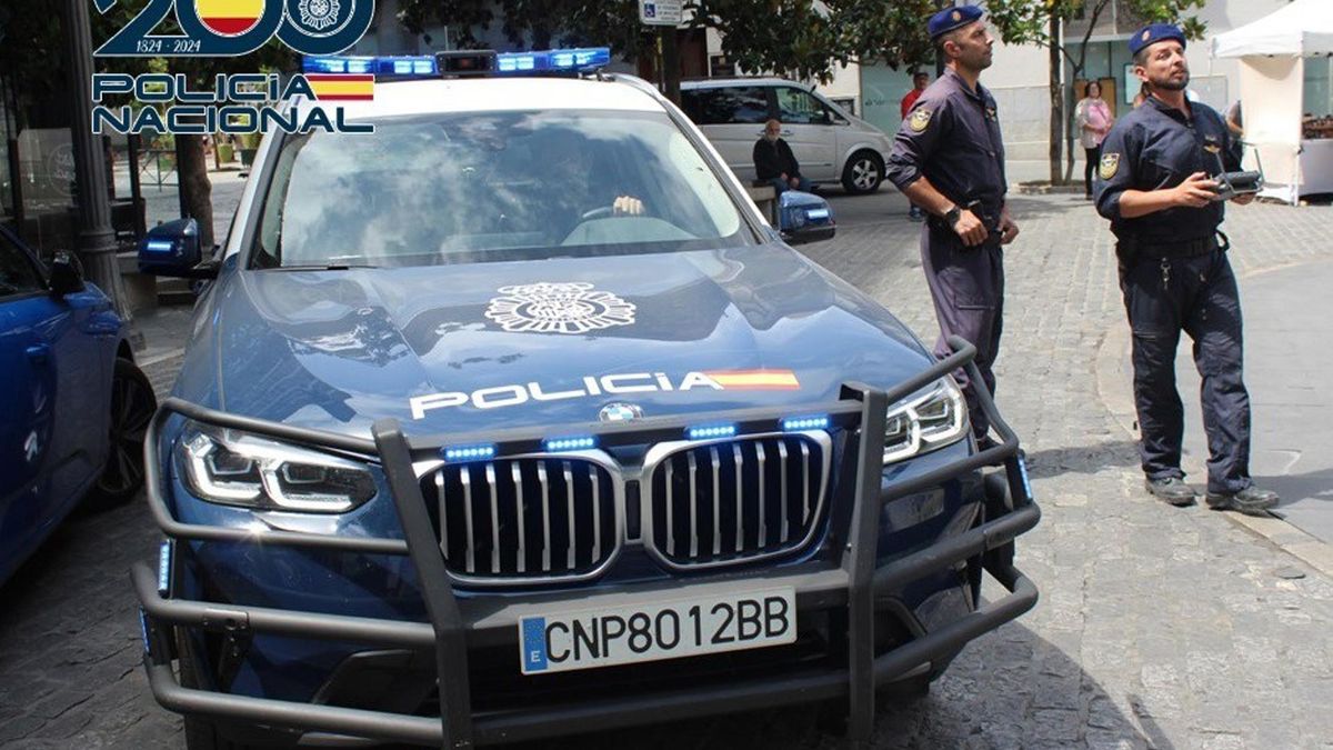 Dos agentes de Policía Nacional junto a un coche patrulla