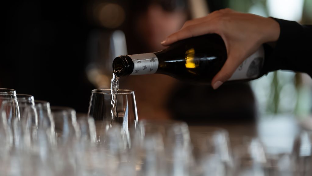 Una camarera sirve copas de vino blanco en un bar de Barcelona