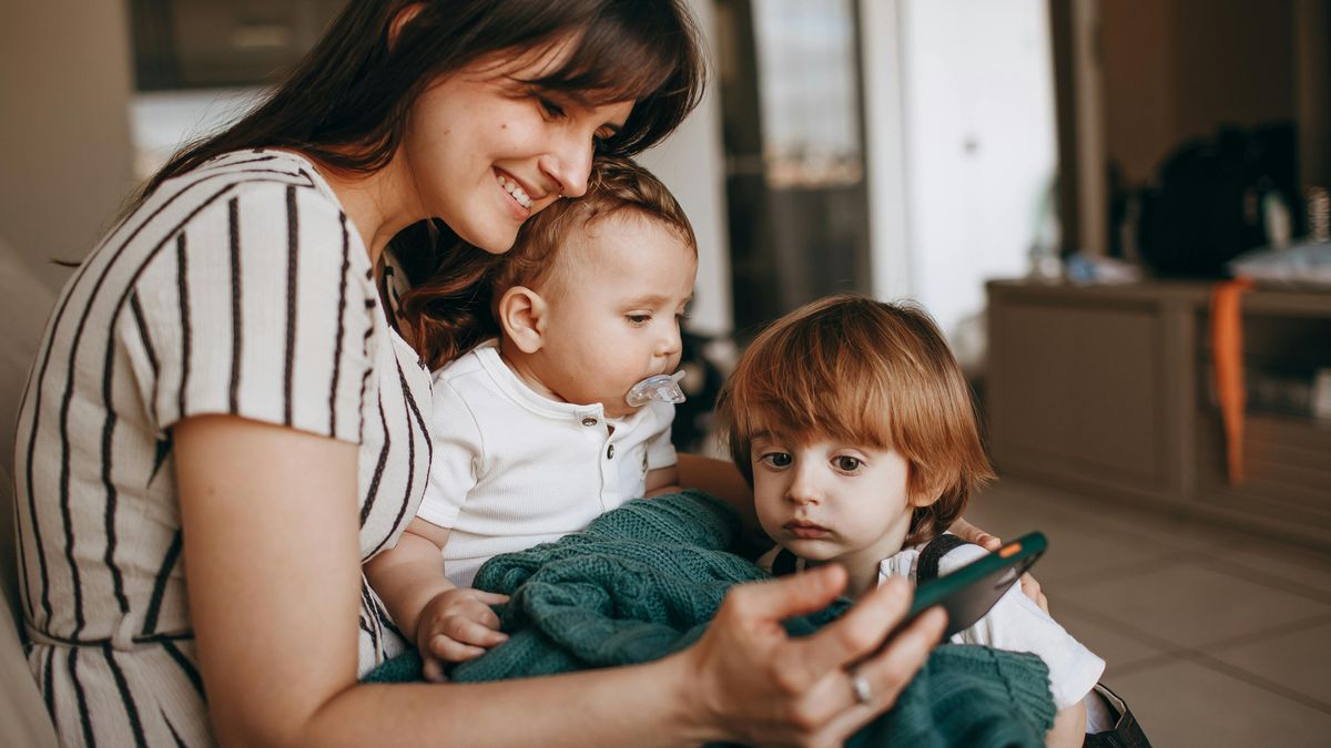 Una madre usando el móvil con sus hijos