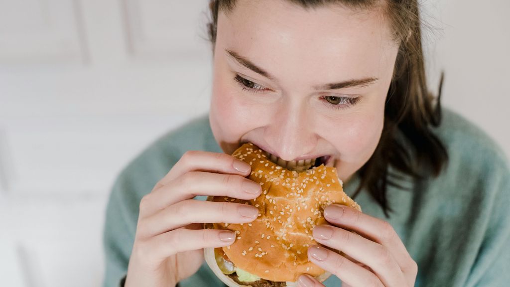 Una chica comiendo una hamburguesa