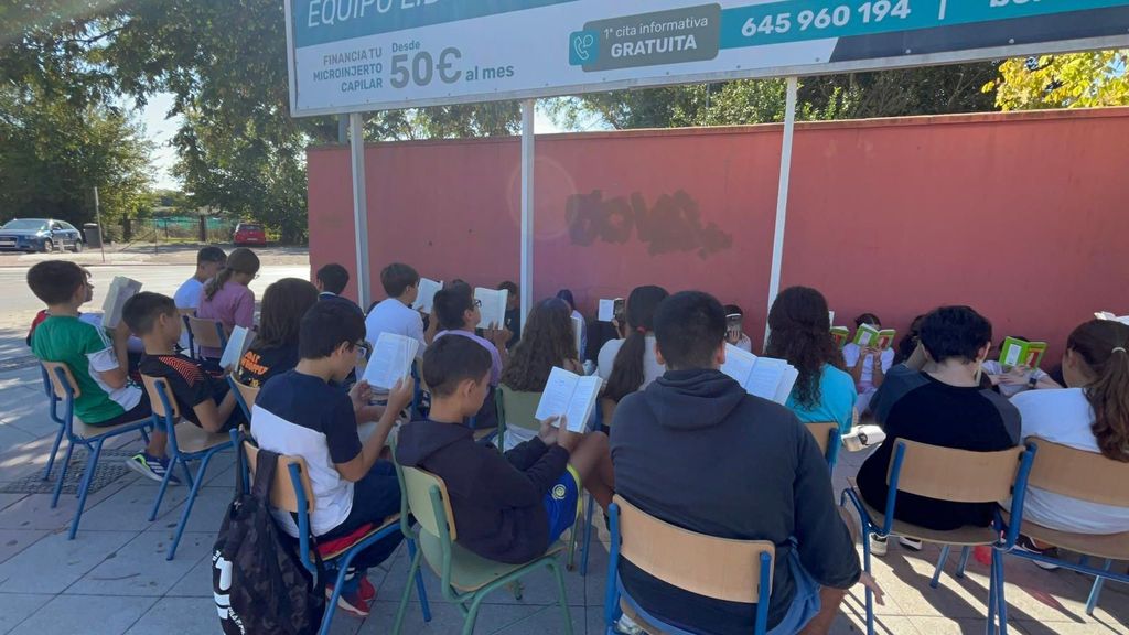 Los alumnos leen un libro en la puerta del instituto