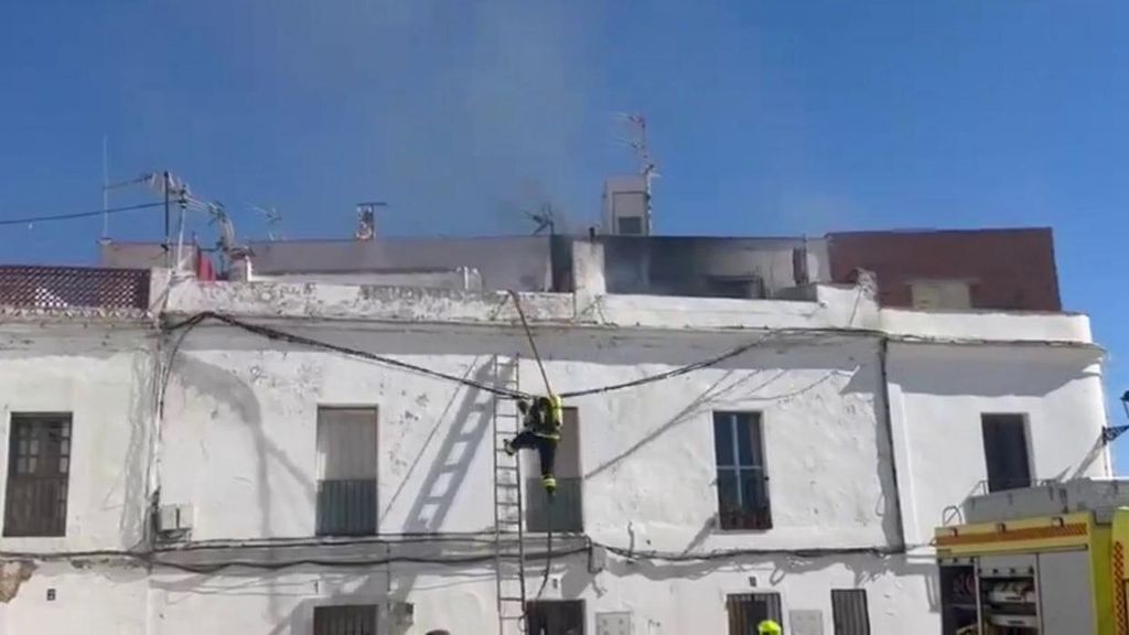 Un bombero cae al suelo durante las labores de extinción de un incendio en una vivienda en Tarifa