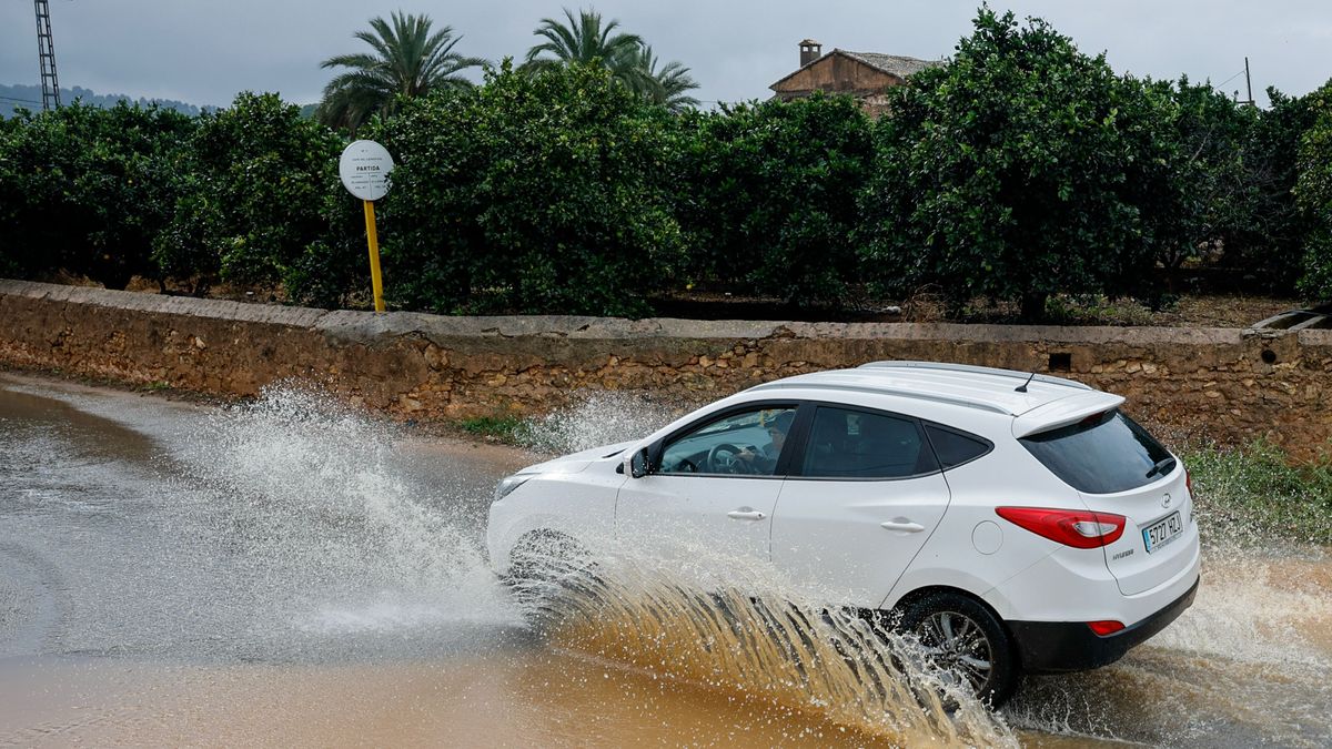 Un coche circula por un camino anegado en Carcaixent