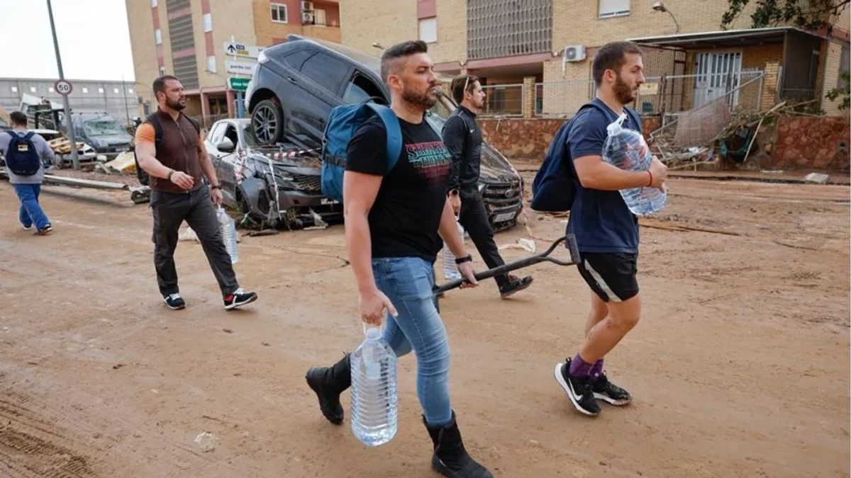 Varios residentes llevan garrafas de agua a la entrada de la localidad de Paiporta, Valencia.