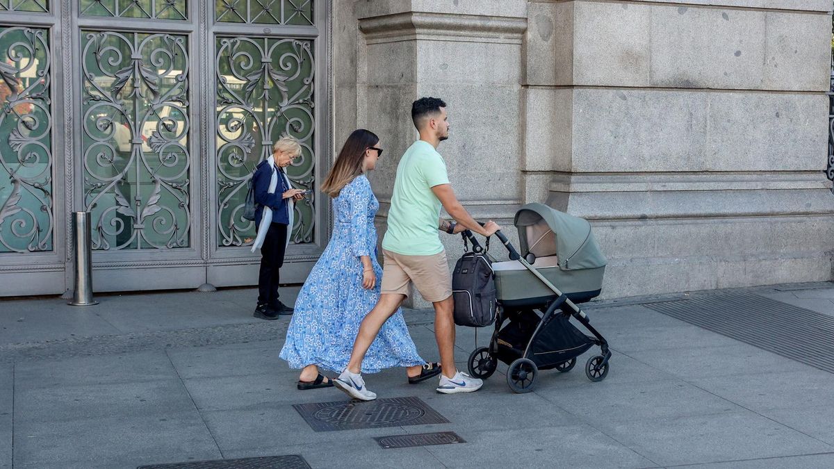 Unos padres pasean con un carrito de bebé.