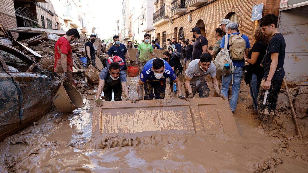 Varias personas retiran el lodo acumulado en una calle de Paiporta, en Valencia