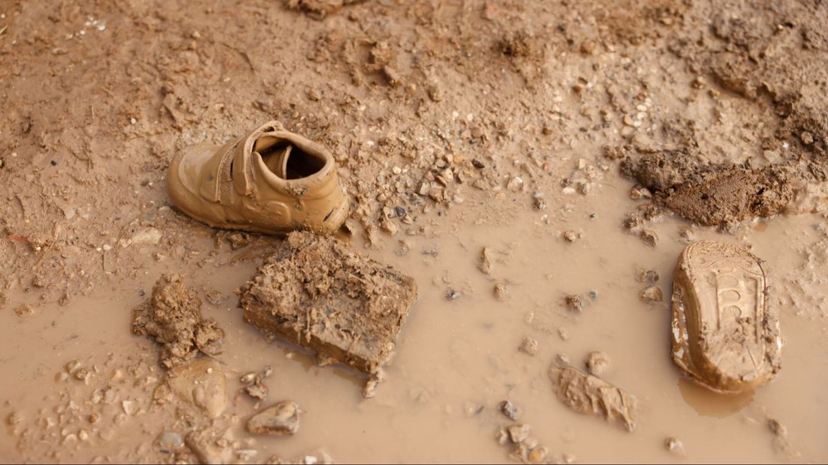 Detalle de un par de zapatillas infantiles cubiertas de lodo en una zona anegada de La Torre (Valencia)