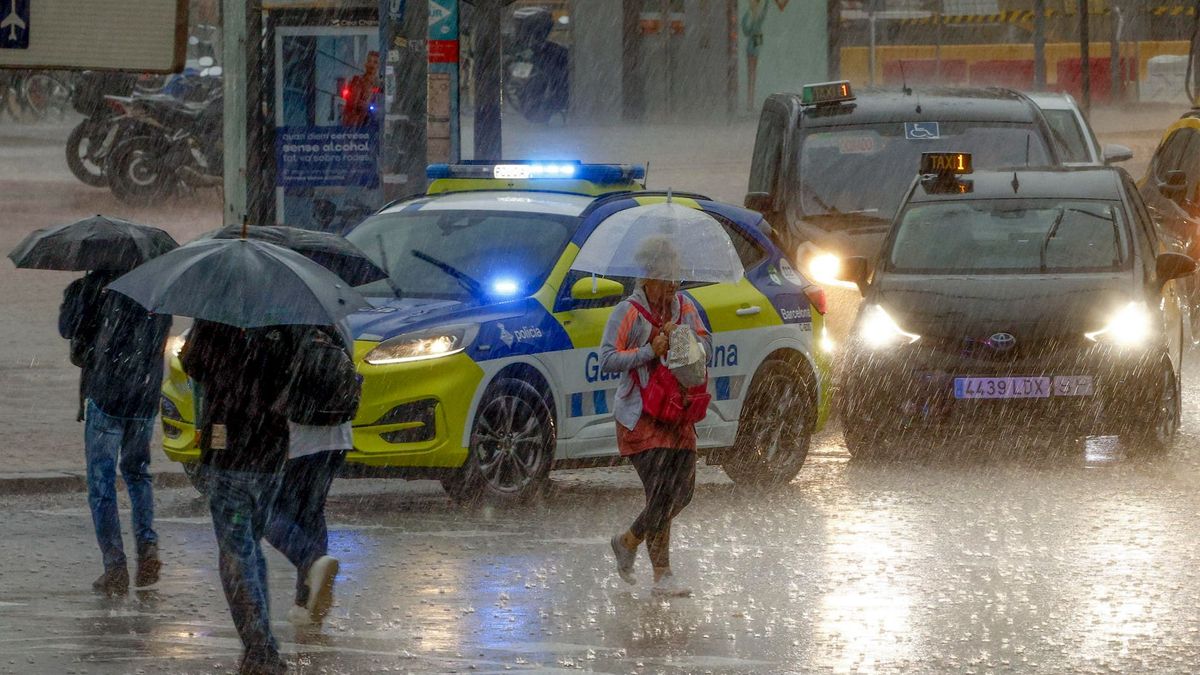 Varias personas se protegen de la lluvia en la Plaza de Espanya de Barcelona este lunes.