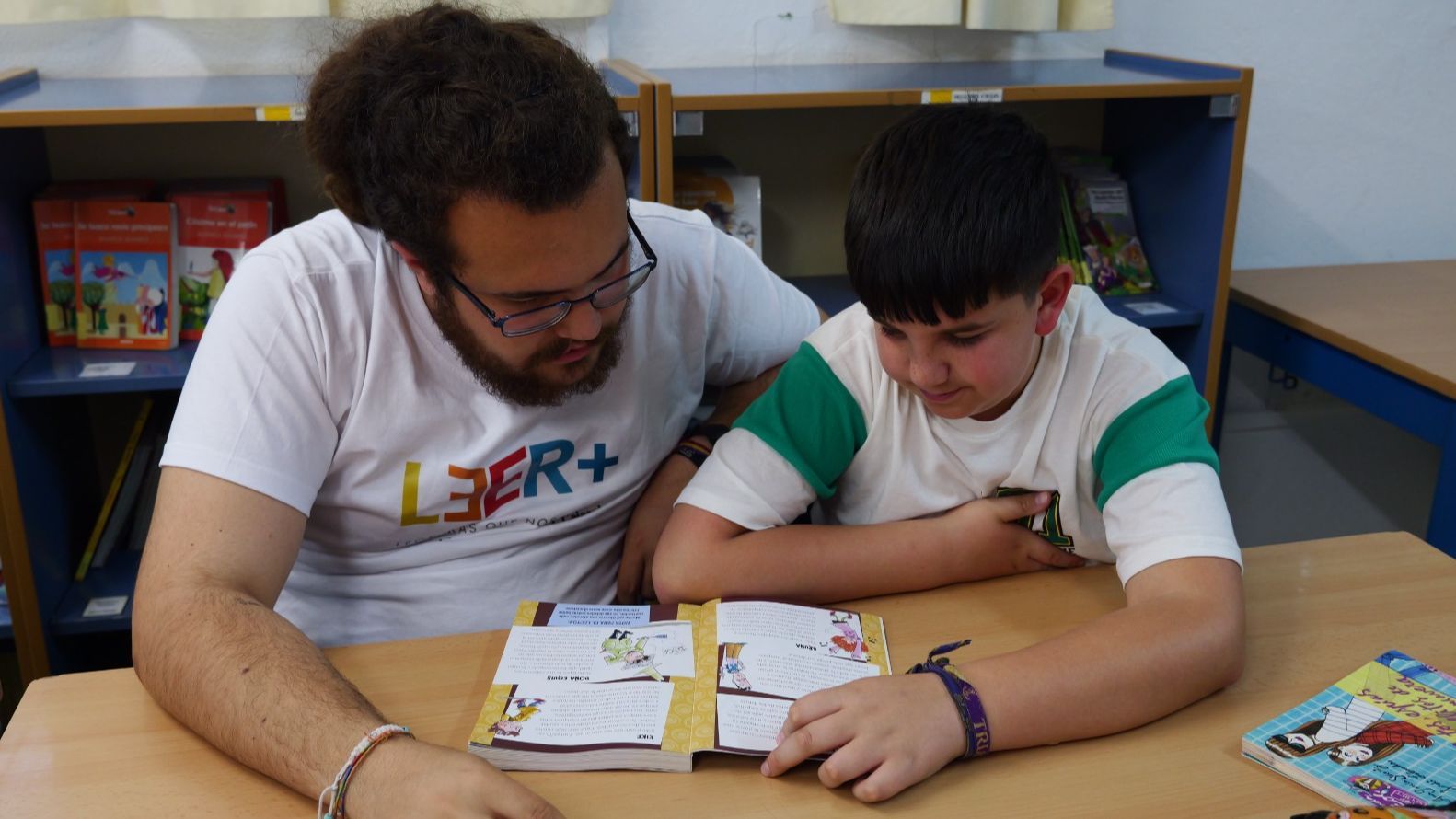 Un voluntario de la Fundción acompaña a un niño en la lectura