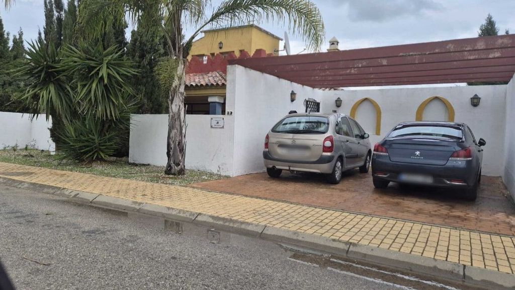 Fachada del chalet con los coches de los supuestos okupas aparcados en la puerta