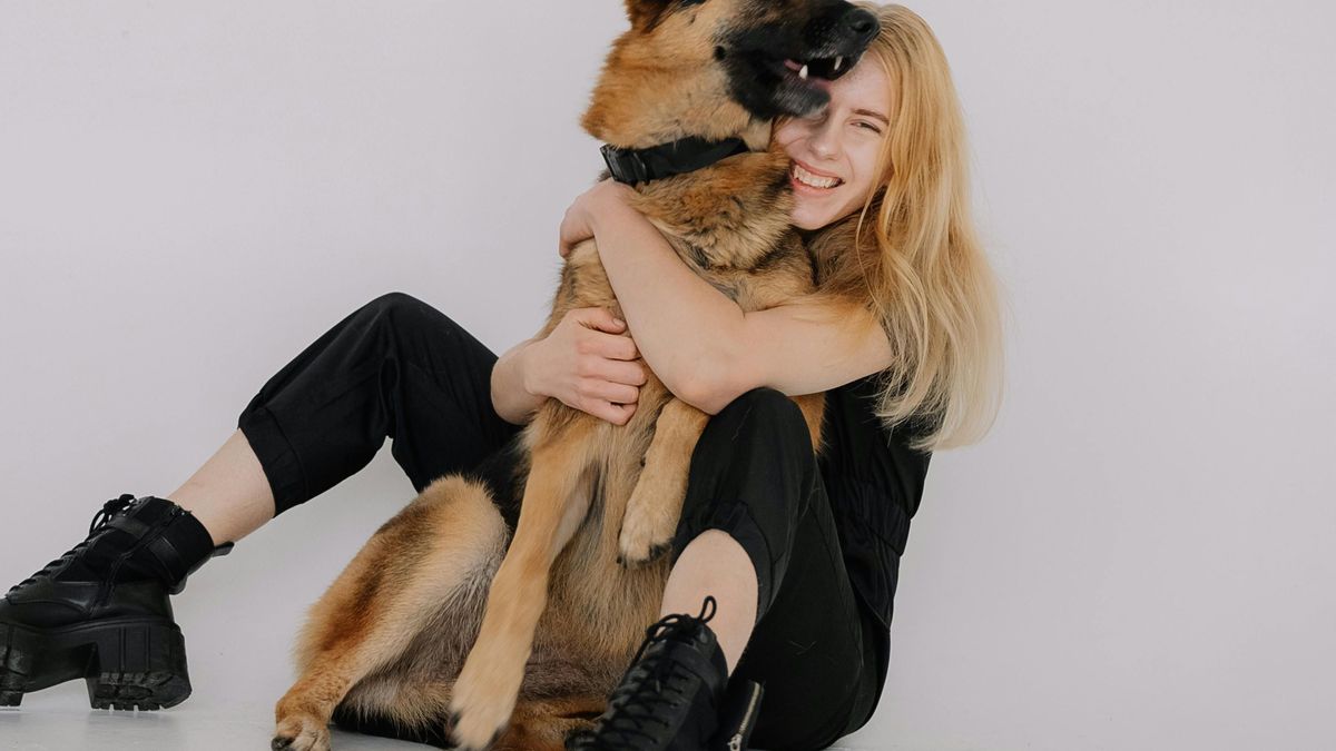 Mujer que abraza a su perro y calza unas botas negras