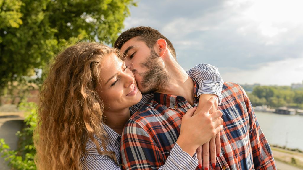 Un hombre besa a una mujer que lo abraza