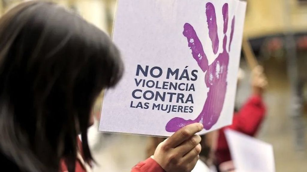 Una mujer camina junto a un cartel contra la violencia de género.