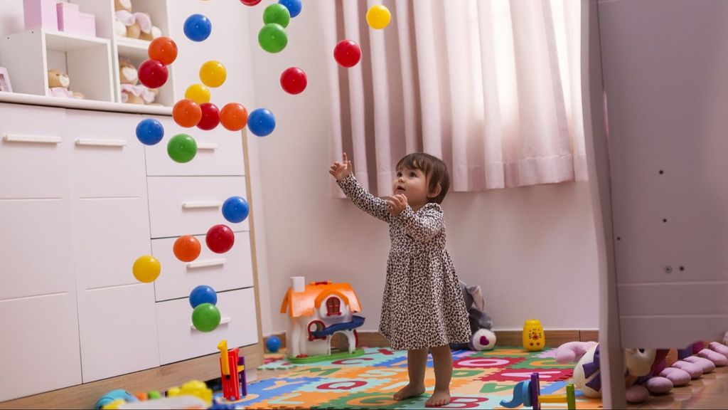 Una niña tirando al aire pelotas de colores