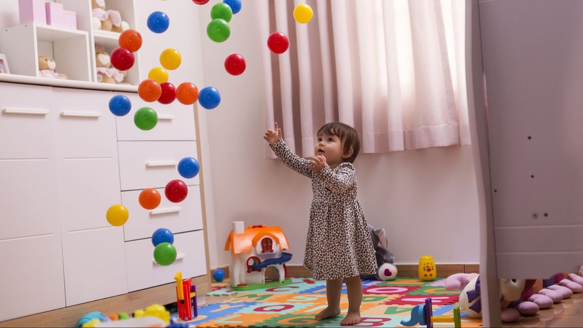 Una niña tirando al aire pelotas de colores