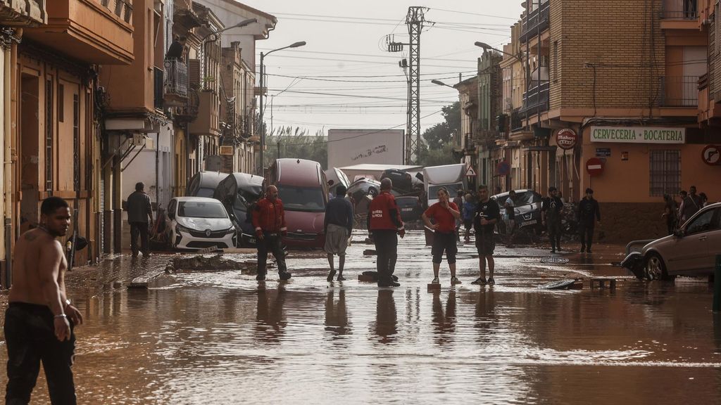 Varias personas en una calle llena de agua tras el paso de la DANA por el barrio de La Torre de Valencia