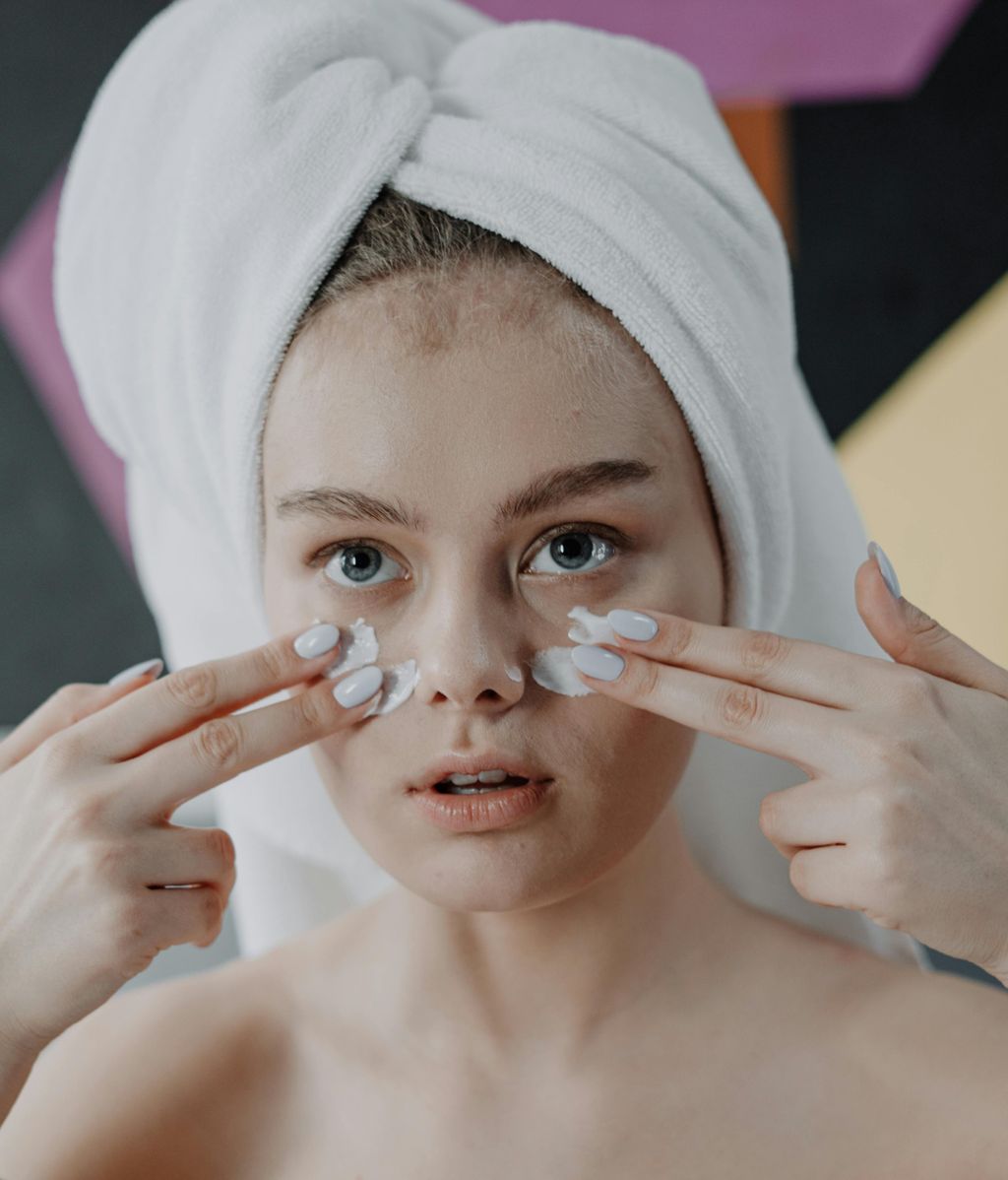 Mujer joven aplicándose crema en el rostro