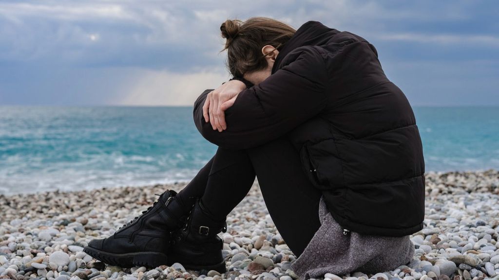 Una joven llorando en una playa