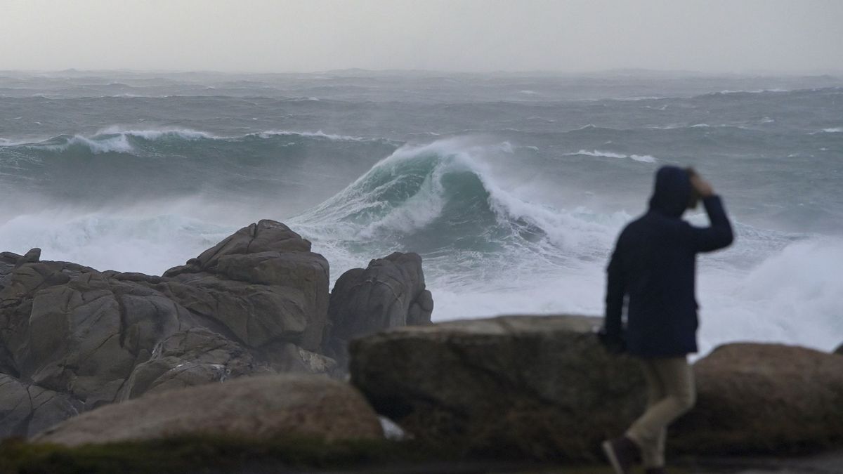 Una persona camina por el paseo marítimo observando el mar embravecido en A Coruña