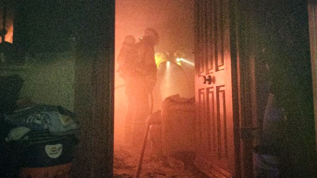 Los bomberos trabajan en el interior de la vivienda calcinada