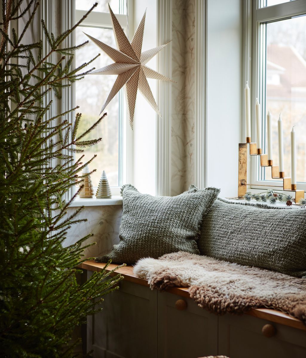 Rincón con ventana y banco decorados con estrellas y velas de Navidad