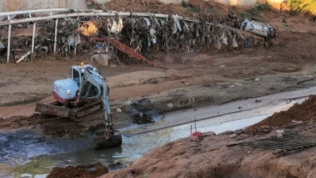 Una máquina retira agua y lodo estancados en el barranco del Poyo