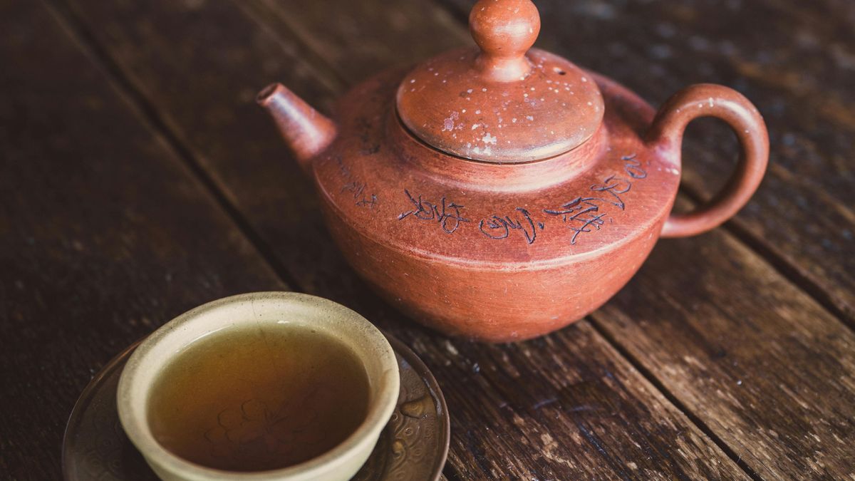 Tetera junto a una taza con infusión