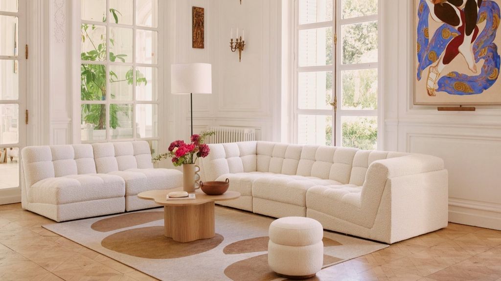 Salón con dos sofás bol de color blanco, alfombra, mesa de centro de madera y cuadros