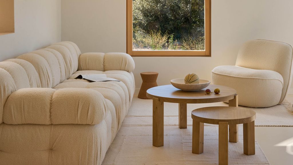 Salón con sofá y sillón de tejido bouclé y mesa de centro de madera