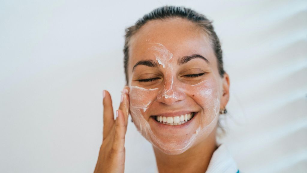 Una joven se aplica un producto cosmético