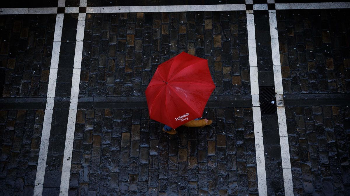 Un viandante se protege de la lluvia en Pamplona