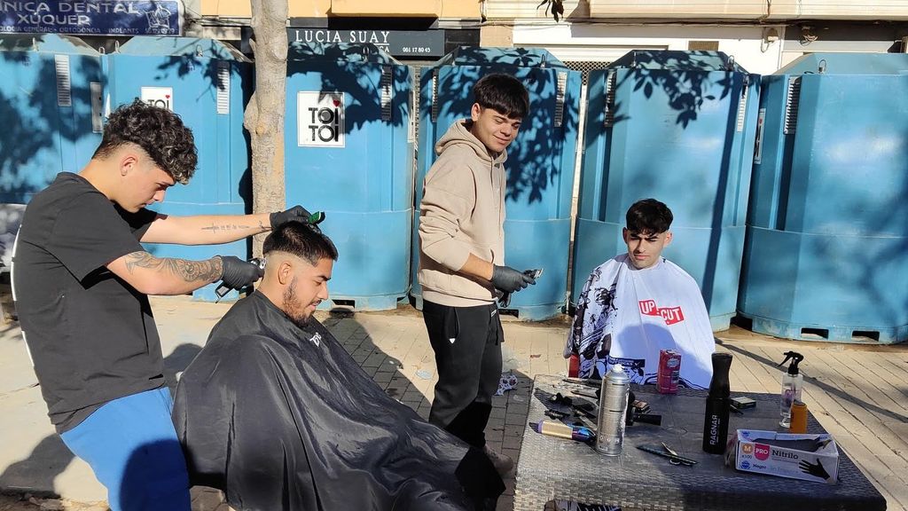 Mario cortando el pelo a un cliente en la plaza donde se ha establecido temporalmente