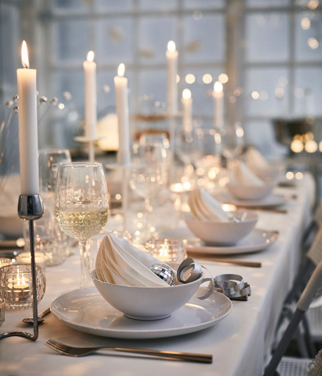 Mesa de Navidad con vajilla y mantel blancos, candelabros plateados y copas con textura