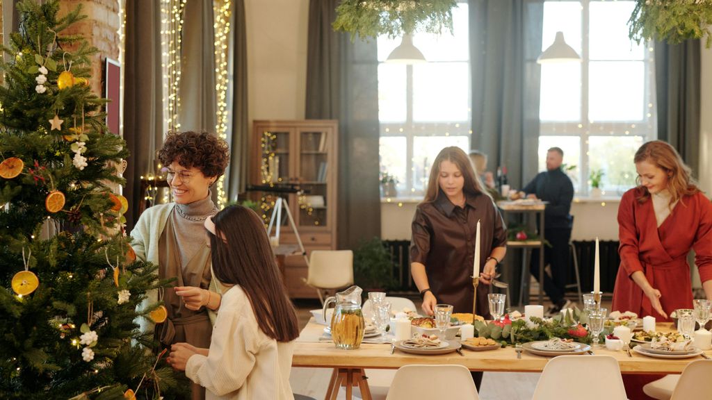 Niñas y mujeres en torno a una mesa y árbol navideños