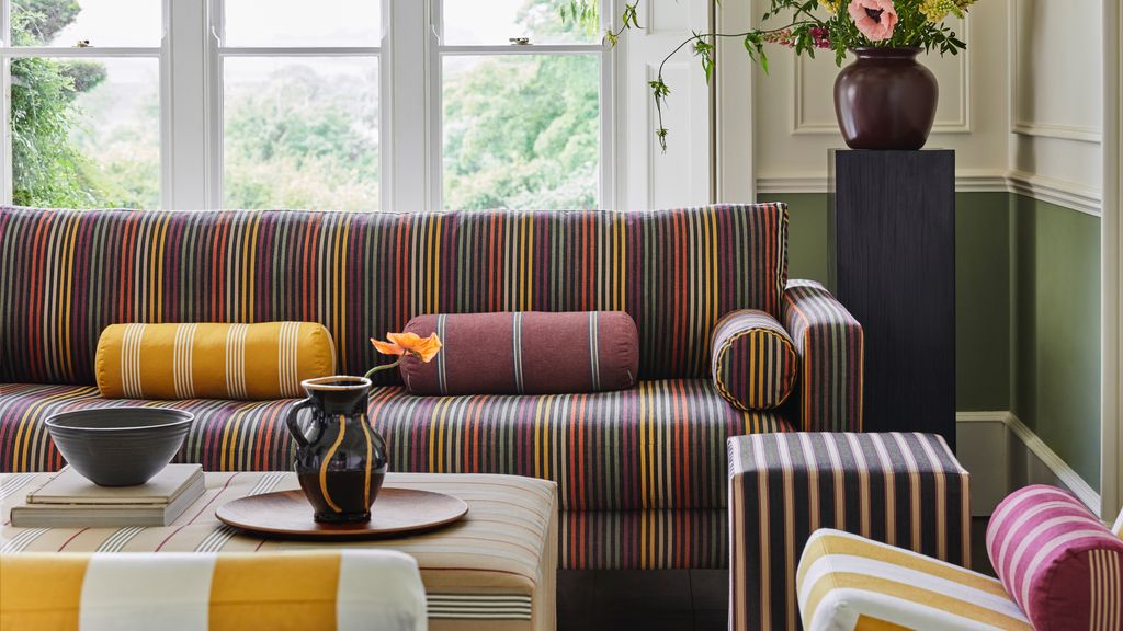 Salón con sofá, mesa de centro tapizada y cojines de rayas de colores