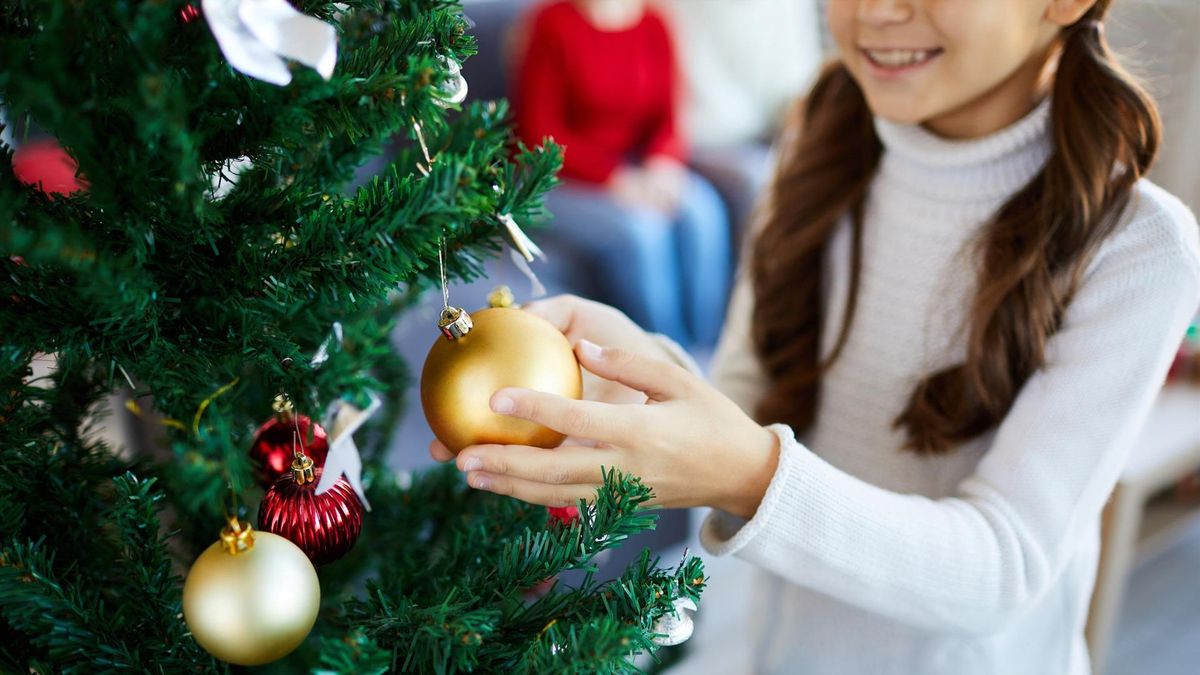 Niña adornando el árbol de Navidad