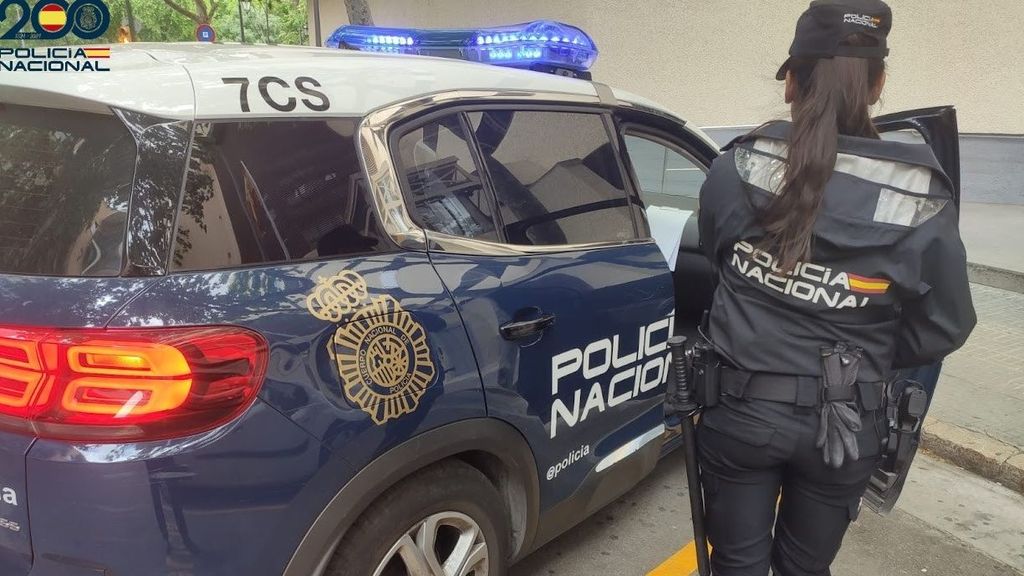 Una agente de la Policía Nacional junto a un coche patrulla.