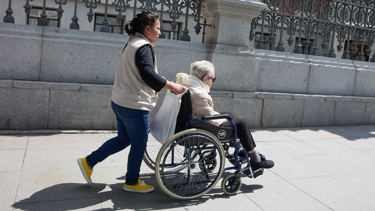 Una cuidadora pasea a una mujer dependiente en Madrid