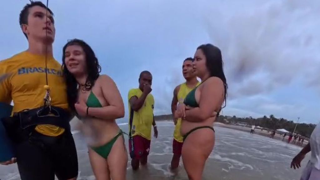 La bañista rescatada se abraza a Bruno Lobo tras ser atendida por los socorristas en la playa de San Luis, Brasil