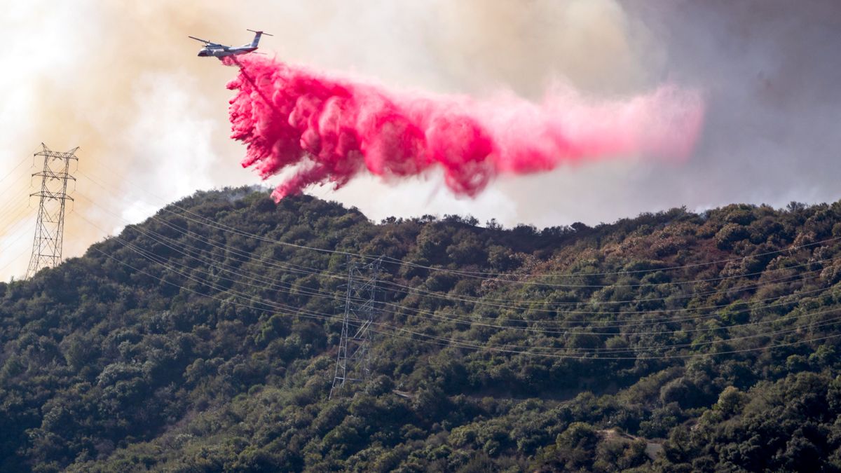 Un avión libera miles de litros de agua mezclados con Phos-Chek o 'polvo rosa' para extinguir los incendios de Los Ángeles